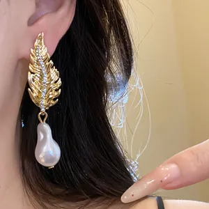 Elegant vintage gold feather earrings adorned with crystals and a Baroque pearl drop