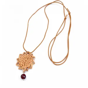 Collier bohème avec pendentif en fleur tressée, cordon ajustable et perle rouge.