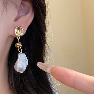 Detail of vintage baroque pearl drop earrings on model's ear, elegant gold finish.