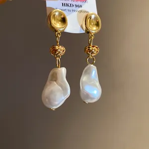 Detail shot of vintage baroque pearl drop earrings with golden knot and 925 silver tag