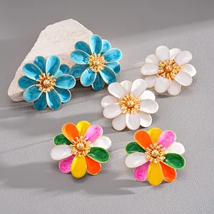 Detailed view of vibrant enamel flower stud earrings on a textured stone surface.