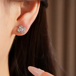 Detailed close-up of a sparkling zircon clover flower stud earring worn on ear