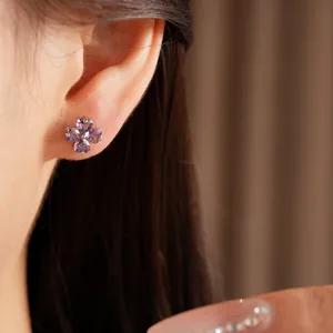 Detailed close-up of a purple zircon lucky clover stud earring worn on a female ear