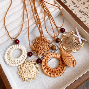 Gros plan détaillé de pendentifs bohèmes en paille tressée avec perles en bois et cuir.