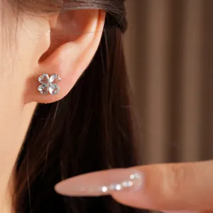 Detailed shot of elegant silver earrings with light blue heart-shaped zircon clover.