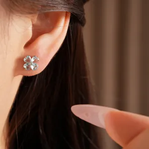 Detailed macro shot of sparkling blue zircon clover stud earring worn on ear lobe