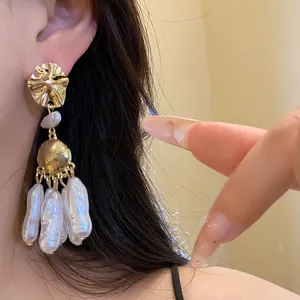 Detailed macro view of elegant baroque pearl drop earrings worn on ear.