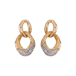 Pendientes elegantes de eslabones dorados con diamantes de imitación sobre fondo blanco.