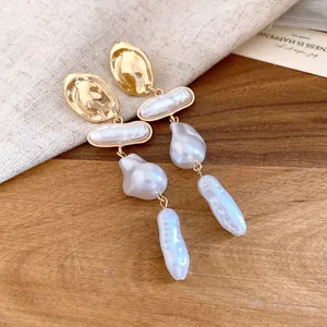 Macro detail of elegant baroque pearl drop earrings featuring vintage gold-toned metal finish