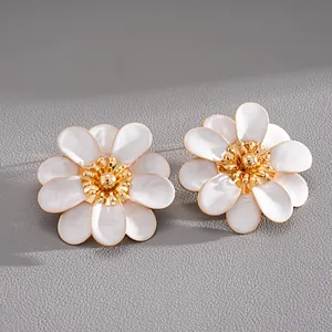 Close-up of white enamel flower stud earrings with elegant gold center and petals.