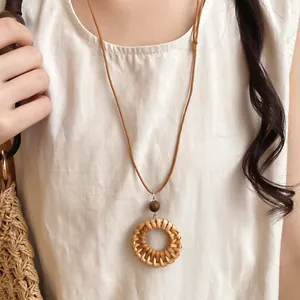 Gros plan du collier bohème en rotin tressé avec perle en bois et cordon en cuir.