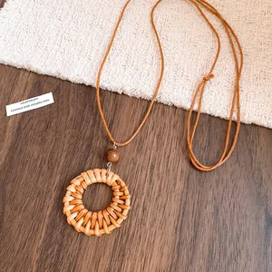 Détail du collier bohème en rotin avec perle en bois et cordon en cuir marron tressé