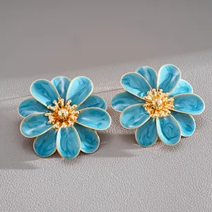 Detailed view of blue enamel flower earrings with gold-tone centers on grey surface