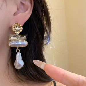 Close-up of vintage baroque pearl drop earrings with gold hammered studs and crystals