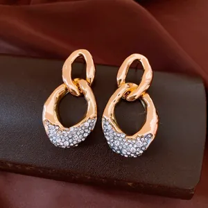 Primer plano de pendientes de cadena dorados con detalle de pavé de diamantes