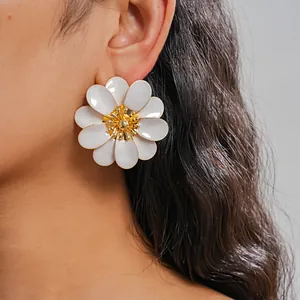 Close-up of oversized white enamel flower stud earring on model's ear for resort style