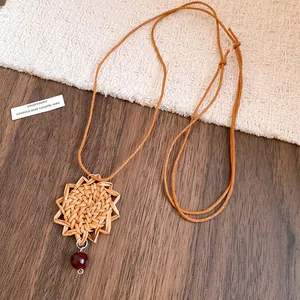 Gros plan d'un collier pendentif fleur tissée de style bohème avec cordon en cuir.
