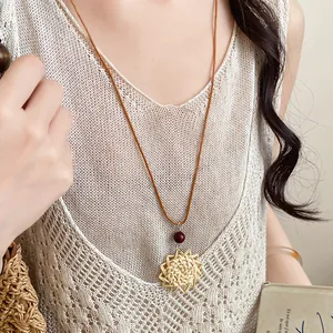 Vue détaillée du pendentif fleur en paille tressée avec perle rouge sur cordon en cuir