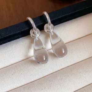 Silver post C-shaped earrings with clear resin teardrop charms in minimalist style