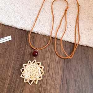 Détail du collier bohème avec pendentif fleur en rotin tressé et perle de bois rouge