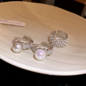 Detailed view of elegant silver open rings featuring lustrous pearls and sparkling zircons.