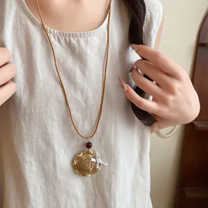 Détail du collier bohème avec pendentif chapeau de paille tressé et perle en bois rouge.