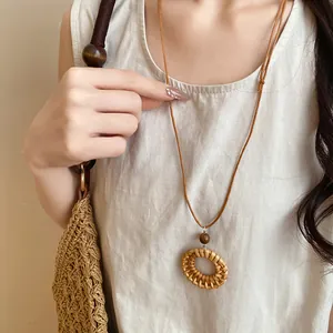 Vue détaillée du collier bohème en rotin tressé avec perle en bois sur un mannequin.