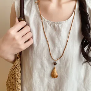 Gros plan d'un collier bohème avec pendentif en rotin tressé et cordon en cuir marron