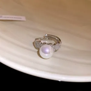 Close-up detail of a silver open ring featuring a shimmering pearl and pavé zircons