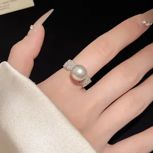 Detailed macro view of an elegant pearl ring with pavé zirconia worn on a finger