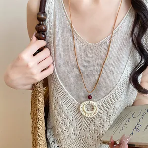 Détail d'un collier bohème avec pendentif tissé, perle en bois et cordon