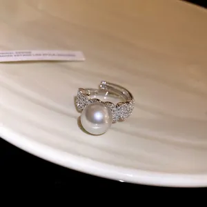 Close-up detail of a silver-tone ring featuring a large pearl and sparkling zircons