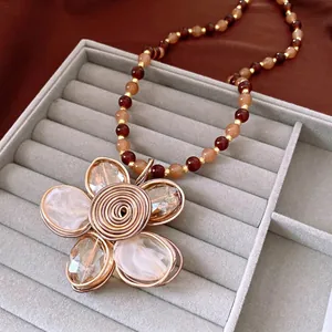 Vintage crystal beaded necklace with large wire-wrapped flower pendant on velvet tray