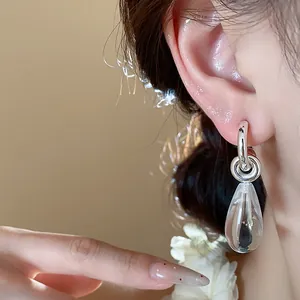 Elegant minimalist silver C-shaped earrings with clear resin teardrop charms on model