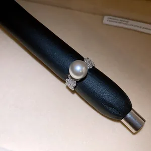 Macro detail of elegant silver-tone ring with large pearl and sparkling zircon clusters