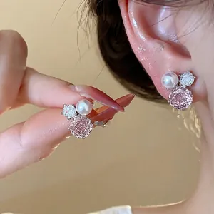 Elegant sterling silver zircon flower and pearl stud earrings worn on ear by a model