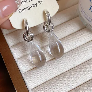 Detailed view of minimalist silver hoop earrings with clear resin teardrop charms
