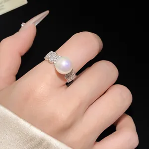Detailed macro shot of an elegant silver bear ring with a large pearl and zircons on finger.