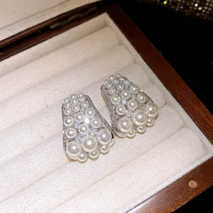 Detailansicht eleganter Silberohrringe mit geclusterten Perlen und glitzernden Zirkonias.