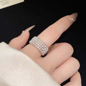 Close-up detail of an elegant silver open ring with multiple rows of white pearls and zircons.