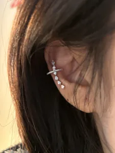 Close-up of sparkling zircon cross ear cuff worn on the ear showing elegant details