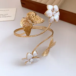 Elegant gold wrap arm cuff with white enameled flowers and detailed butterfly charms