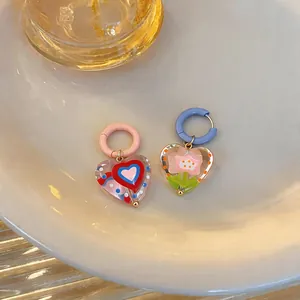 Close-up of sweet dopamine style glazed heart and flower drop earrings on a ceramic plate