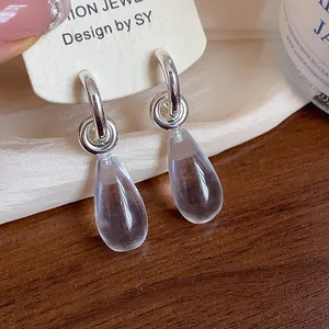 Close-up of minimalist S925 silver hoop earrings with clear resin teardrop pendants
