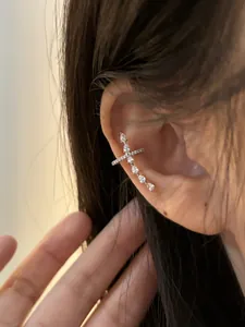 Close-up detail of a minimalist cross-shaped ear cuff with sparkling cubic zirconia