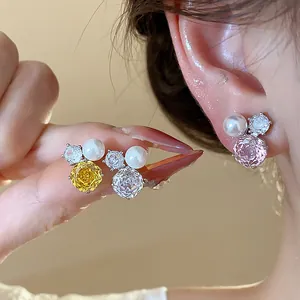 Detail showing flower zircon and pearl stud earrings worn and held for size reference.