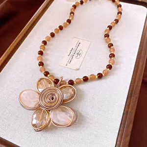 Detail view of vintage beaded necklace featuring a wire-wrapped crystal flower pendant