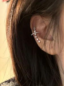 Close-up of a silver cross ear cuff with sparkling pear-shaped cubic zirconia stones.