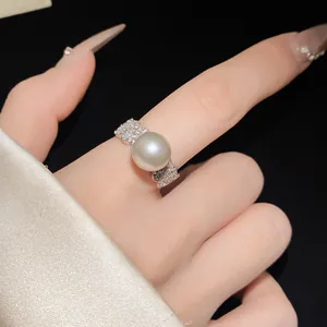 Close-up detail of a delicate silver-tone ring with a large pearl and zircon accents.
