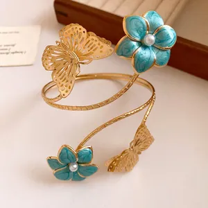 Detail view of a gold spiral arm cuff featuring blue enamel flowers and butterflies